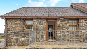 A stone building with a tiled roof, two windows with curtains, and a metal gate. - 2 Bed in Aberystwyth (oc-twlct) (Capel Seion)
