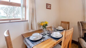 A dining table set with white plates, glasses, and a vase of yellow flowers. - 2 Bed in Aberystwyth (oc-twlct) (Capel Seion)