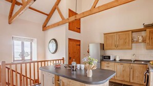 Una cocina con armarios de madera, una isla central, un reloj y una ventana con vistas.