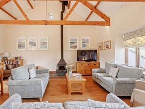 A living room with two grey sofas, a wooden coffee table, a TV, and a fireplace. - 4 Bed in Launceston (oc-brhig) (Launceston)