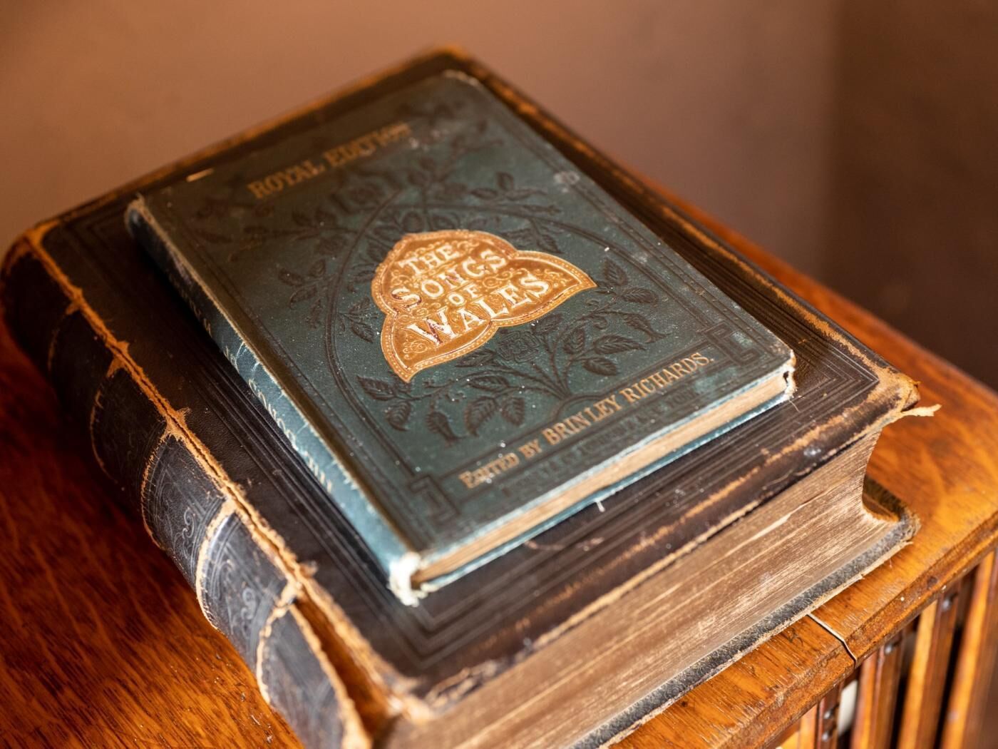 A stack of old books with worn covers, one titled 'The Songs of Vales' by Brinley Richards.