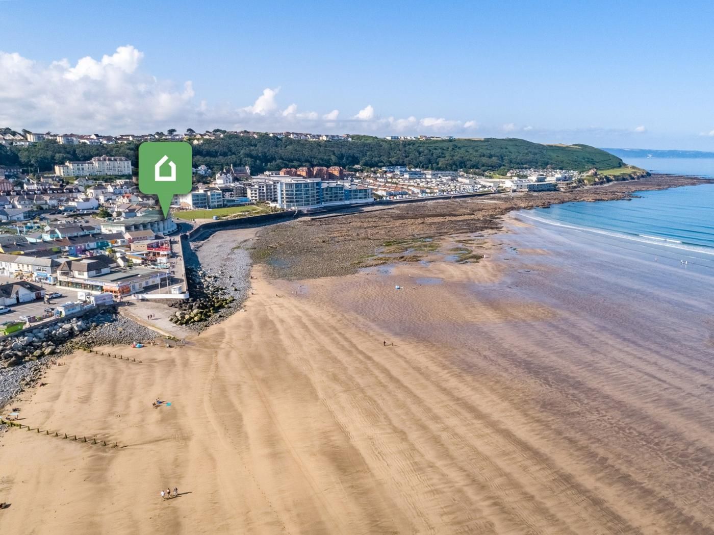 A coastal town with a sandy beach, buildings, and a clear view of the sea.