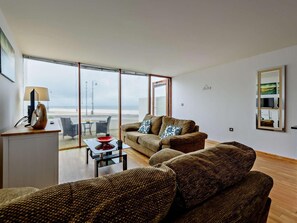 A modern living room with a sofa, a coffee table, and a view of the beach. - 1 Bed in Bideford (oc-nasea) (Westward Ho!)