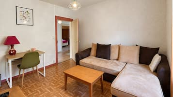 Un salon meublé comprenant un canapé, une table basse en bois, un bureau avec une lampe et une chaise.
