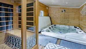Sauna, jossa on puinen sisustus, lasiovi ja poreallas.