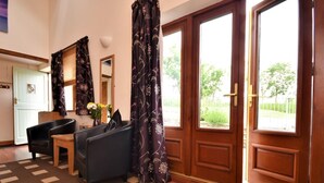 Ein Zimmer mit Holztür, Schreibtisch, Stuhl, Teppich und einem Fenster mit Vorhängen.