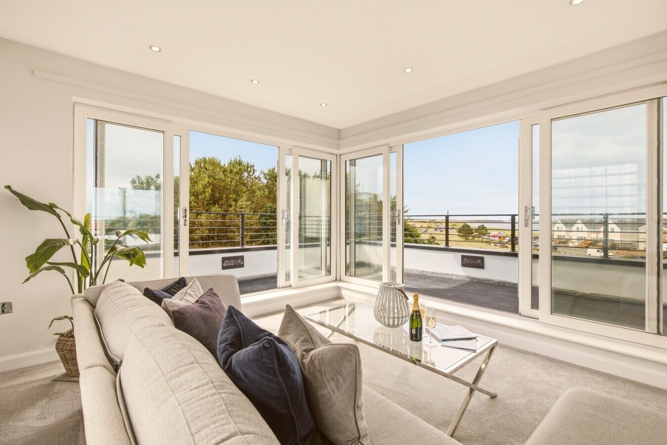 A modern living room with a glass coffee table, a sofa, and large windows offering a view of the city.
