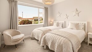 Un dormitorio con dos camas, una silla, una ventana con cortinas y decoraciones con motivos de estrellas en la pared.
