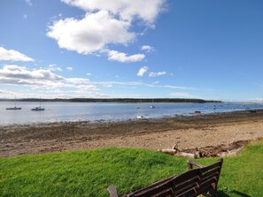 A bench overlooking a beach with boats in the water and a clear sky. - 3 Bed in Elgin (oc-oldfh) (Elgin)
