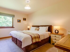 Ein Schlafzimmer mit Bett, Nachttischen, einem Schreibtisch, einem Fenster und einer Deckenleuchte.