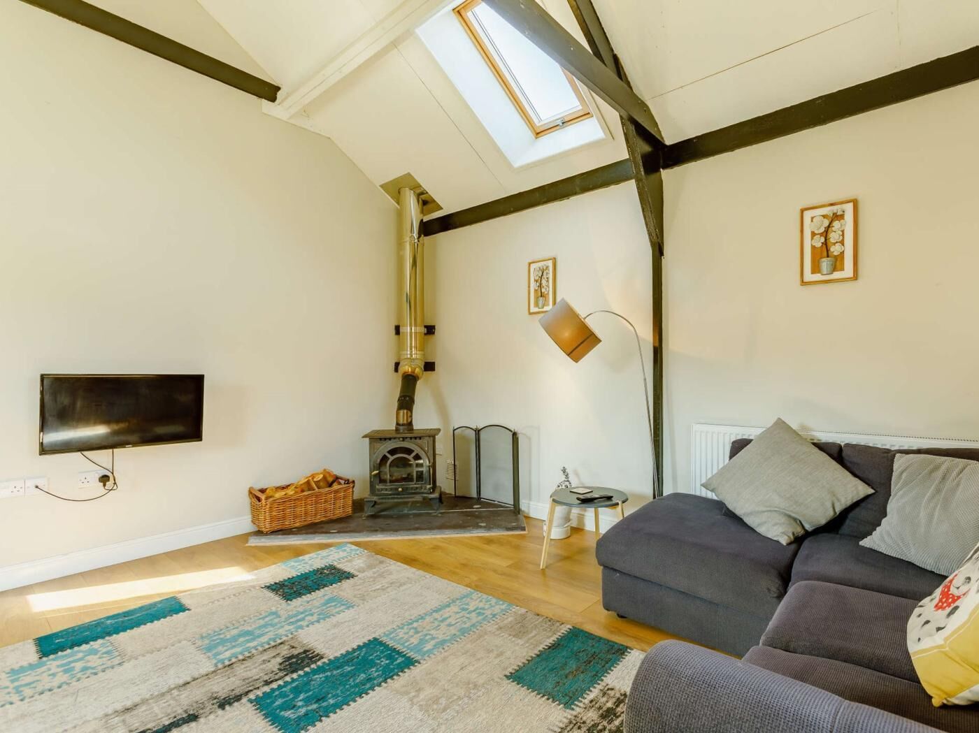 Una sala de estar con sofá, televisión, chimenea y tragaluz.