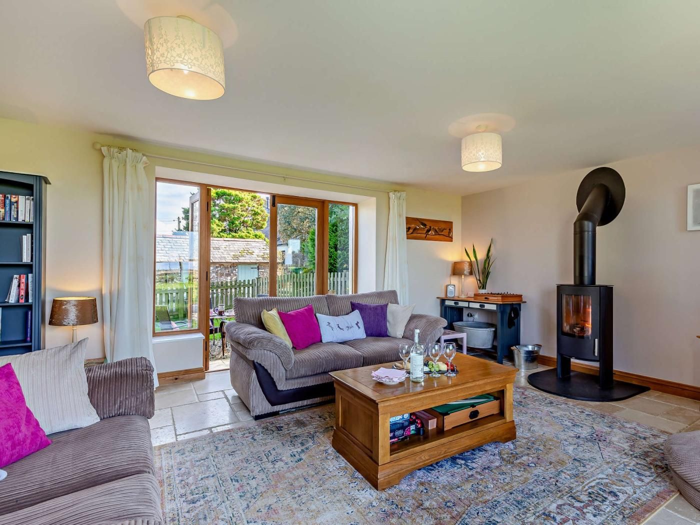 A living room with a sofa, coffee table, bookshelf, and a wood-burning stove.