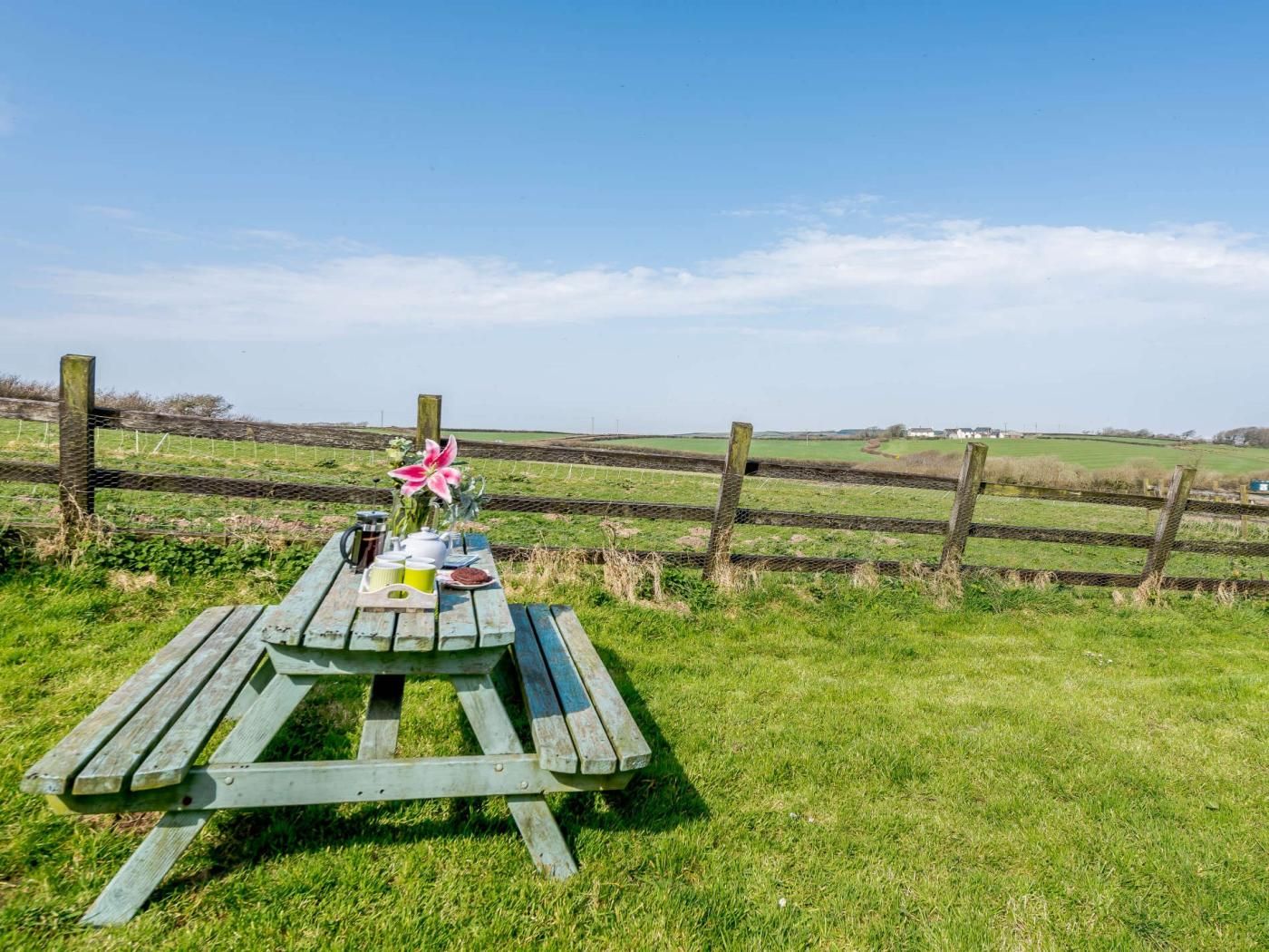 A picnic table with a flower arrangement, a mug, and a plate of food.