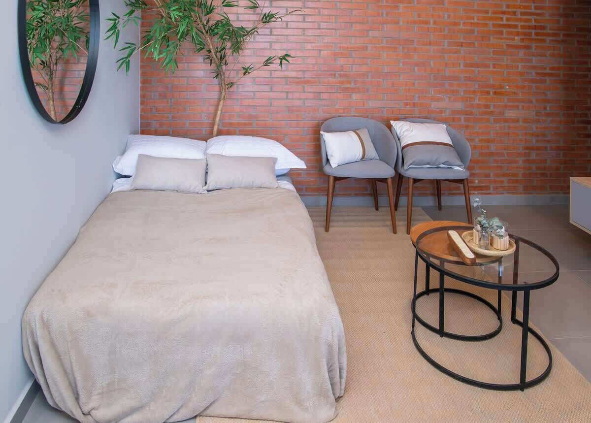 A bedroom with a bed, two chairs, a small round table, and a potted plant.