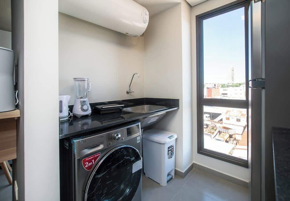 A compact kitchen with a washing machine, a coffee maker, and a sink.