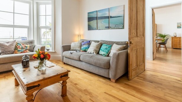 A living room with a sofa, a coffee table, and a painting on the wall. - 5 Bed in Bideford (oc-09156) (Northam)