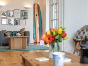 Ein Wohnzimmer mit einer Couch, einem Couchtisch und einem Surfbrett, das an der Wand lehnt.