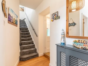 Eine Treppe mit Handlauf, ein an der Wand befestigtes Schild mit der Aufschrift 'HALEWA NORTH SHORE' und ein dekorativer Leuchtturm auf einem Konsolentisch.
