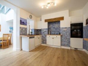 A modern kitchen with white cabinetry, a wooden countertop, and blue-tiled backsplash. - 5 Bed in Bideford (oc-09156) (Northam)