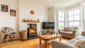 A cozy living room with a fireplace, a television, and comfortable seating. - 5 Bed in Bideford (oc-09156) (Northam)