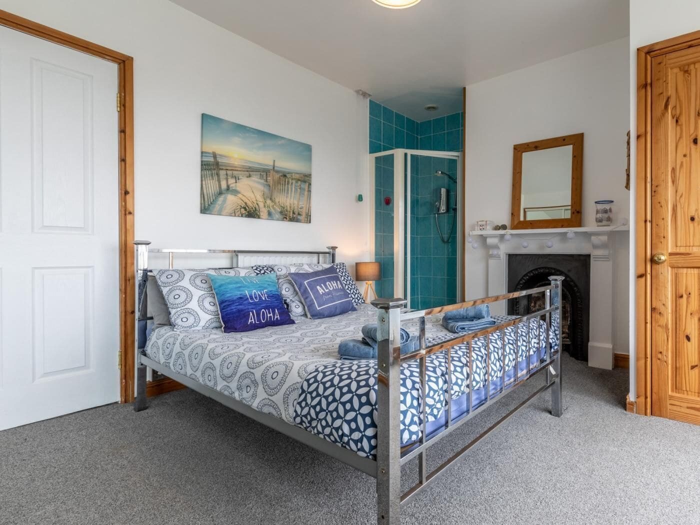 A bedroom with a bed, a shower, a fireplace, and a door.