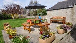 A patio with a wooden table, benches, an umbrella, and potted plants. - 2 Bed in Huntly (oc-ab171) (Huntly)