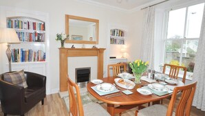 A dining room with a fireplace, bookshelves, and a dining table set for four. - 2 Bed in Huntly (oc-ab171) (Huntly)