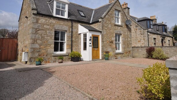 A stone house with a gravel driveway, a wooden door, and a small garden. - 2 Bed in Huntly (oc-ab171) (Huntly)