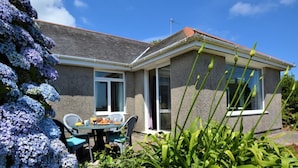 A house with a patio, a table with chairs, and a window. - 2 Bed in Falmouth (oc-tvean) (Constantine)