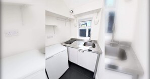 Eine kleine Küche mit Spüle, einem Kühlschrank und einem Fenster für natürliches Licht.