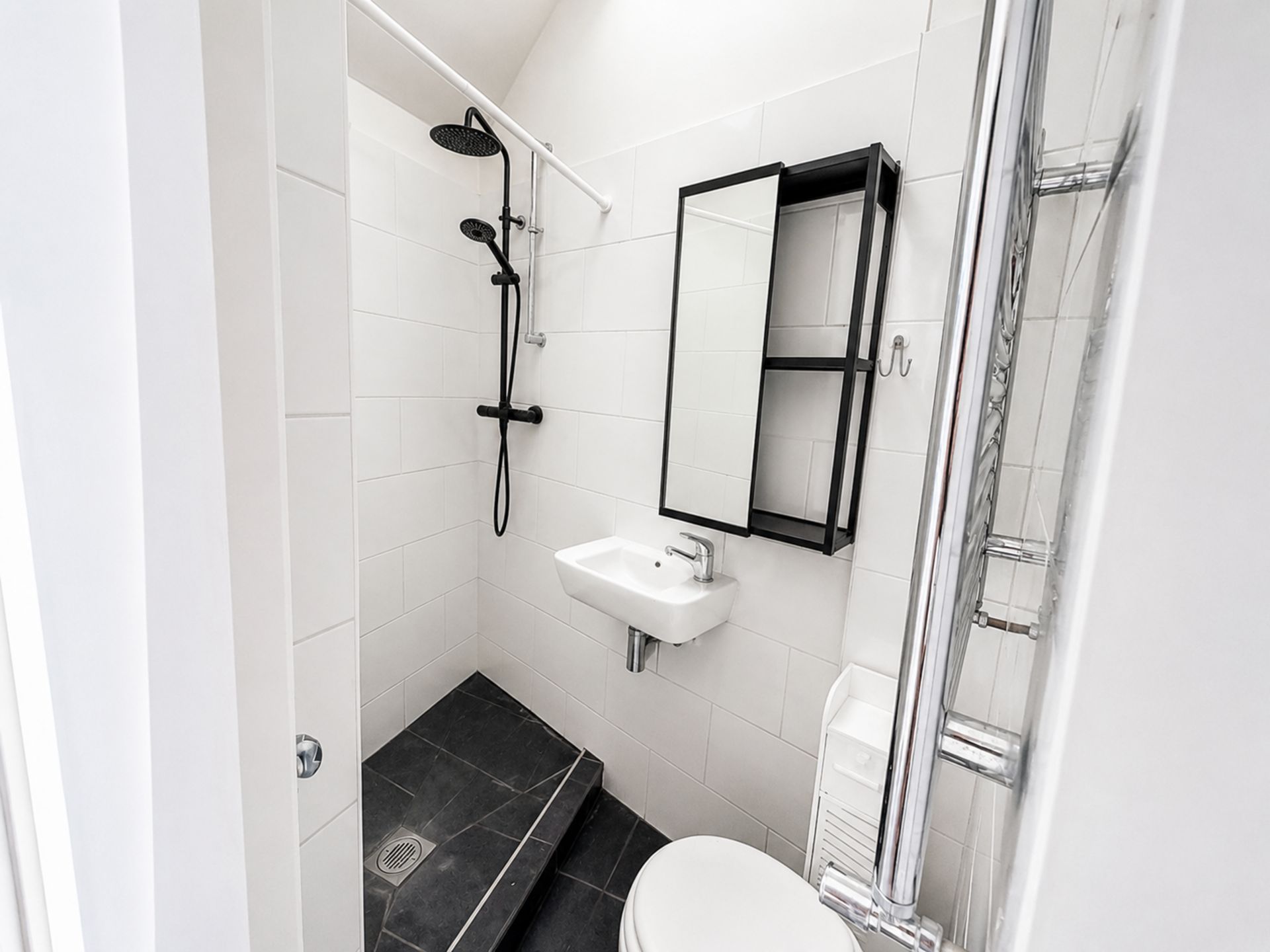 A modern bathroom with a shower, sink, toilet, and a glass shower enclosure.