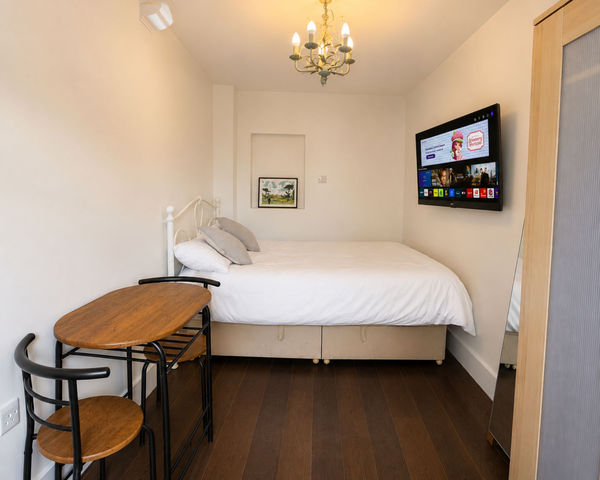 A small, neatly arranged room with a bed, a table, and a chair.