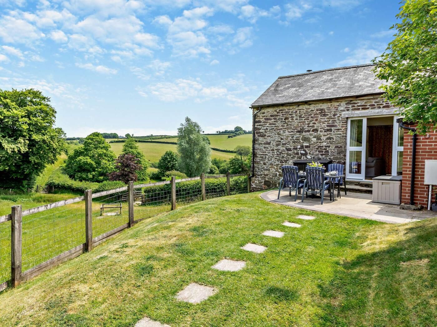 Un cottage in pietra con patio, un giardino recintato e vista sulle dolci colline.