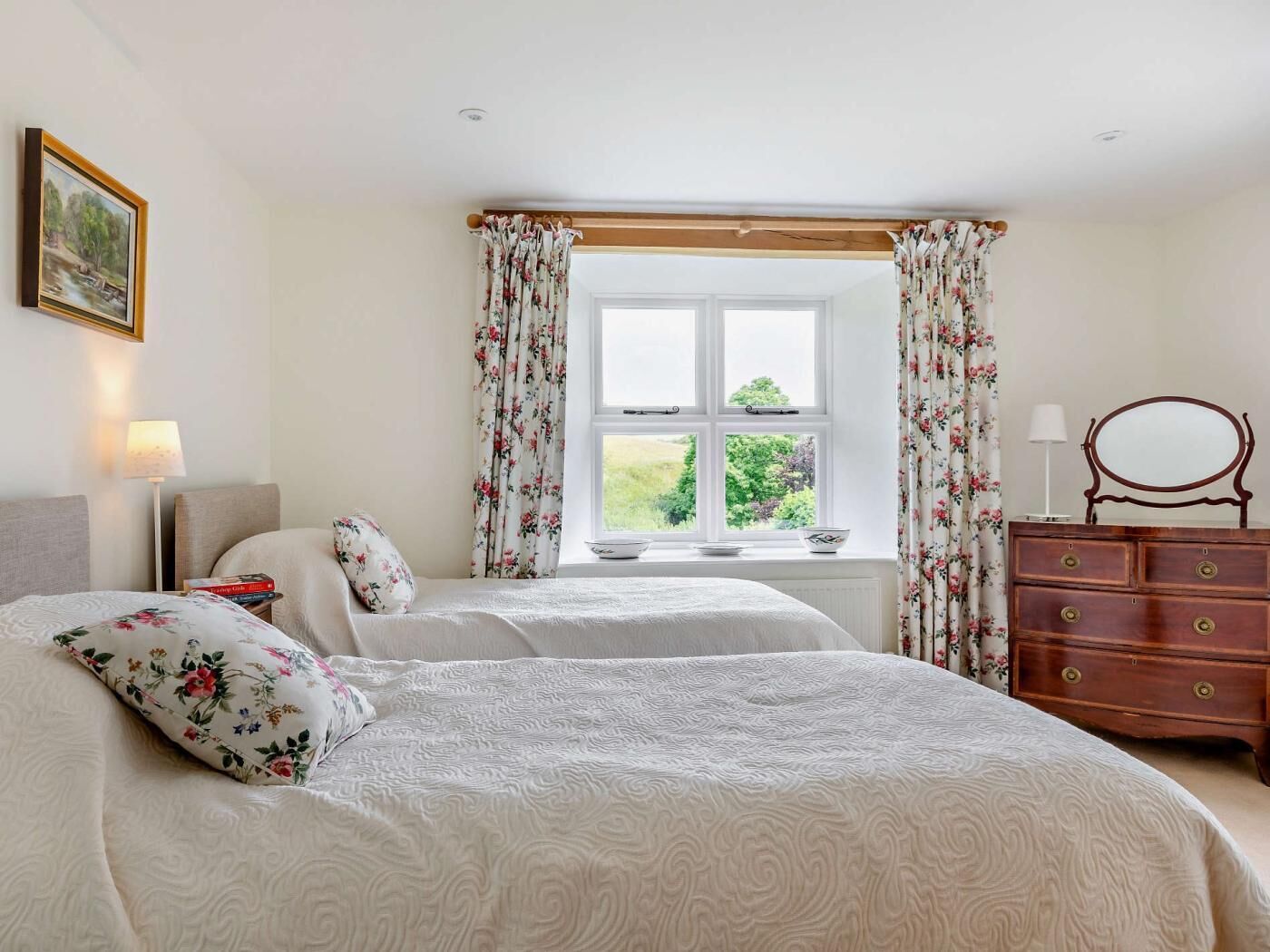 Une chambre à coucher avec un lit, une commode, une table de chevet et une fenêtre avec des rideaux.