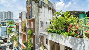 Un edificio a più piani con balconi, alcuni dei quali adornati da piante, e un cielo sereno.