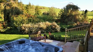A hot tub in a garden with a wooden deck and a bench. - 3 Bed in Dunsyre (oc-lk15m) (Walston)