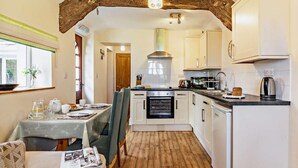 A compact kitchen with white cabinets, a built-in oven, and a coffee maker. - 1 Bed in Ilfracombe (oc-parsc) (Berrynarbor)