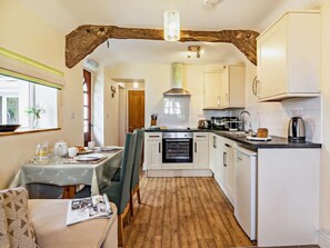 A compact kitchen with white cabinets, a built-in oven, and a coffee maker. - 1 Bed in Ilfracombe (oc-parsc) (Berrynarbor)