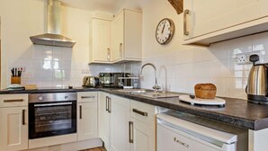 A kitchen with white cabinets, a stainless steel range hood, a microwave, a toaster, a sink, and a loaf of bread on the counter. - 1 Bed in Ilfracombe (oc-parsc) (Berrynarbor)