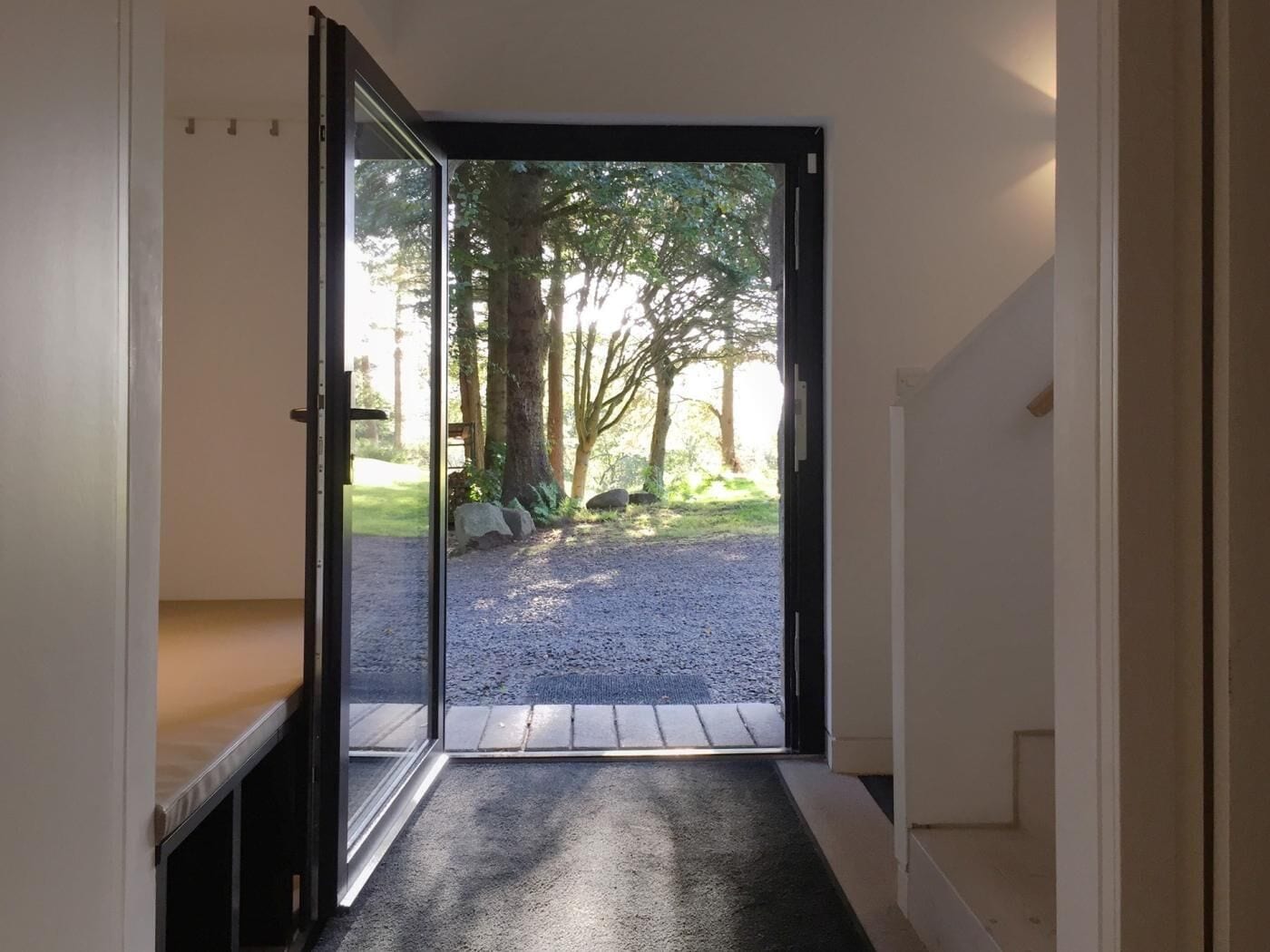 A hallway leading to a glass door with a view of a gravel path and trees outside.