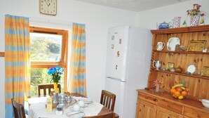 A kitchen with a dining table set for four, a refrigerator, wooden cabinets, and a window with curtains. - 1 Bed in Lairg (oc-su304) (Lochinver)