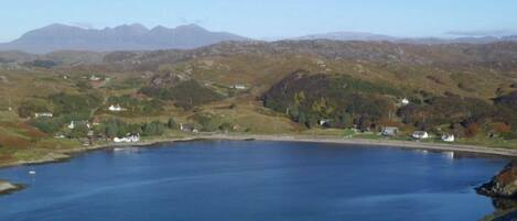 Un lac entouré de collines, avec quelques bâtiments visibles au loin.