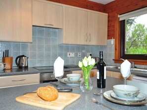 A modern kitchen with wooden cabinets, a granite countertop, and a view of greenery outside. - 2 Bed in Lairg (oc-su306) (Lochinver)