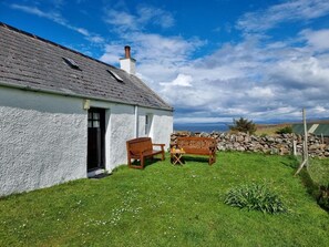 A white house with a grey roof, a stone wall, and a grassy yard. - 2 Bed in Lairg (oc-su187) (Lochinver)