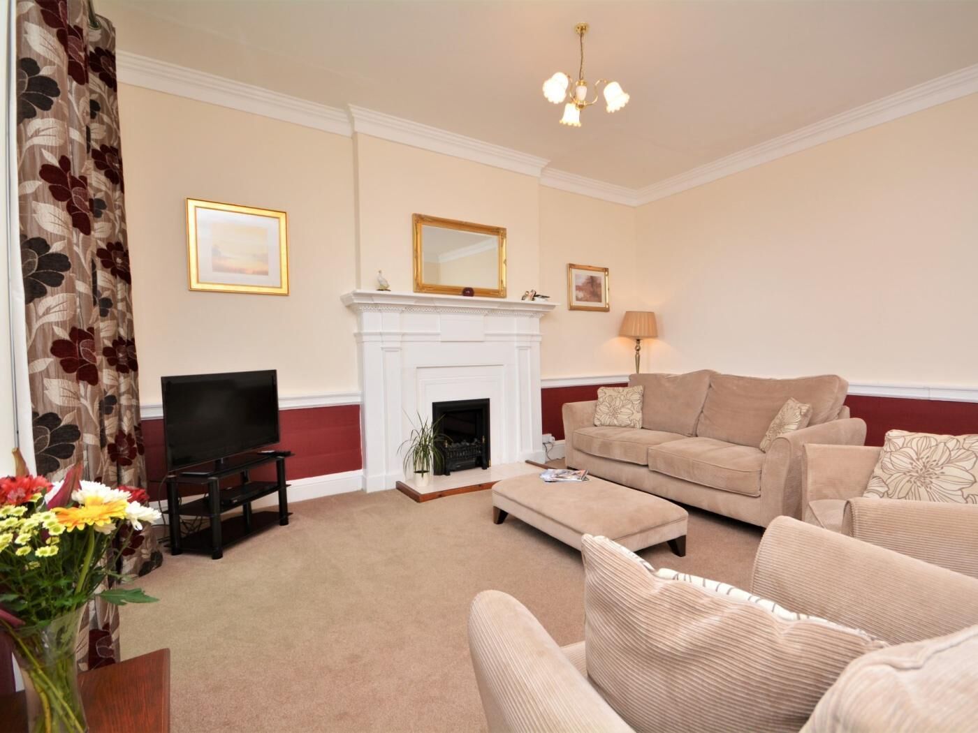Olohuone, jossa on takka, televisio, sohva ja kattokruunu.