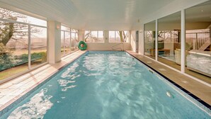 Une piscine intérieure avec des parois en verre transparent, offrant une vue sur l’extérieur, et une bouée de sauvetage placée au bord du bassin.