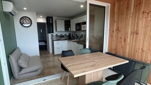 Un intérieur moderne comprenant une table à manger, des chaises, un canapé et un coin cuisine.