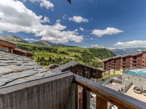 Un resort de montaña con piscina, edificios de madera y vistas a las colinas circundantes.