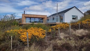 A modern two-story house with large windows and a wooden deck. - 3 Bed in Lairg (oc-su164) (Scourie More)