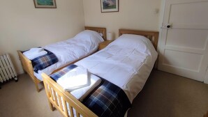 A room with two single beds, a radiator, and two framed pictures on the wall. - 3 Bed in Lairg (oc-su164) (Scourie More)